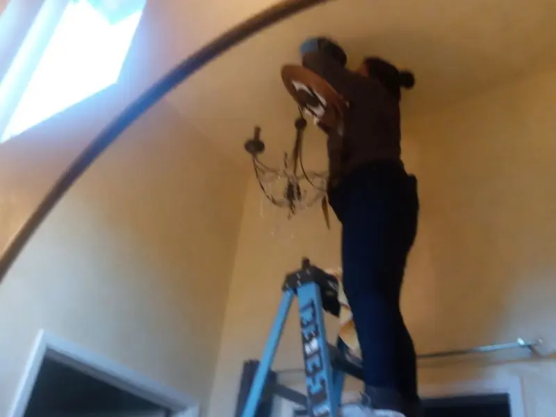 Electrician installing a chandelier in a Somerset residence